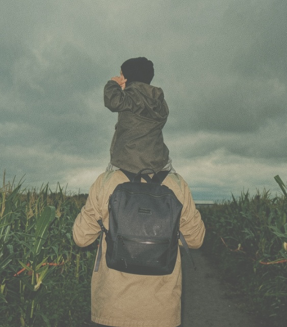 Marcello with his child on his shoulders, walking through a field